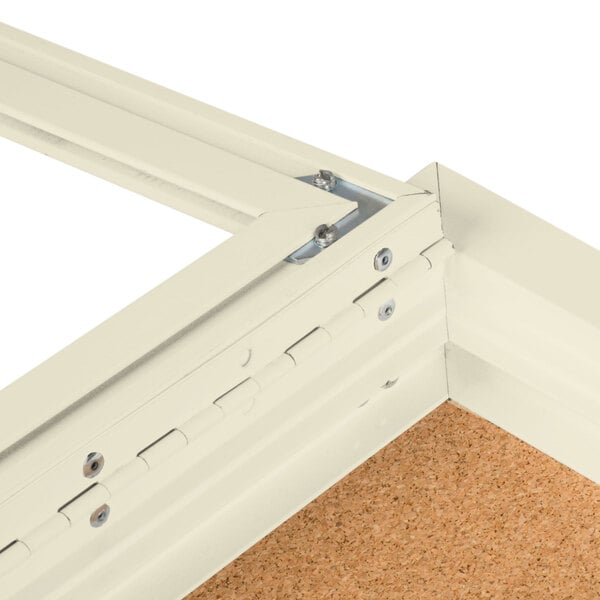 A white Aarco bulletin board cabinet frame with hinges.