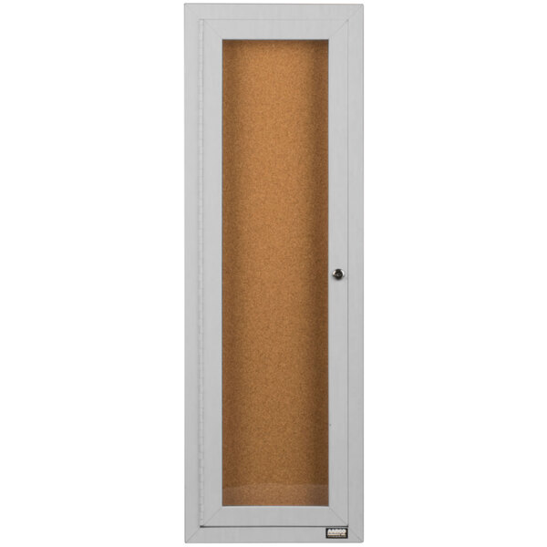 A white rectangular door with a glass panel covering a cork board.