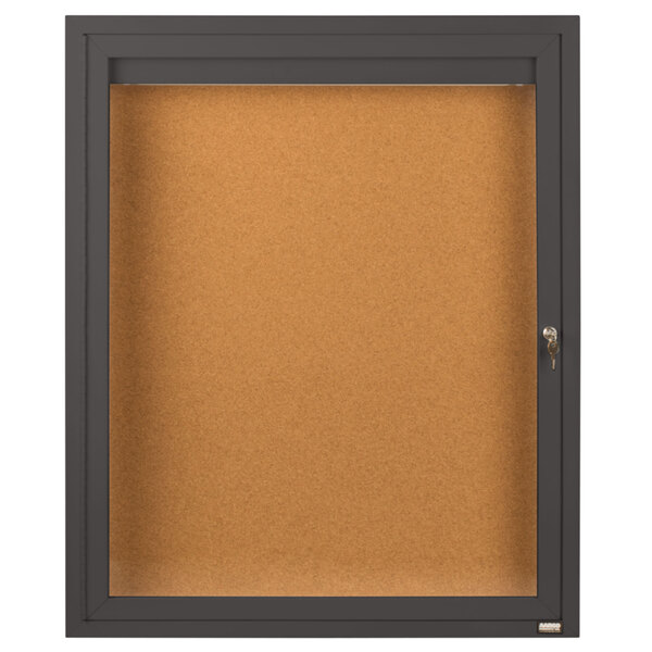 A brown Aarco bulletin board cabinet with a glass door and key lock.