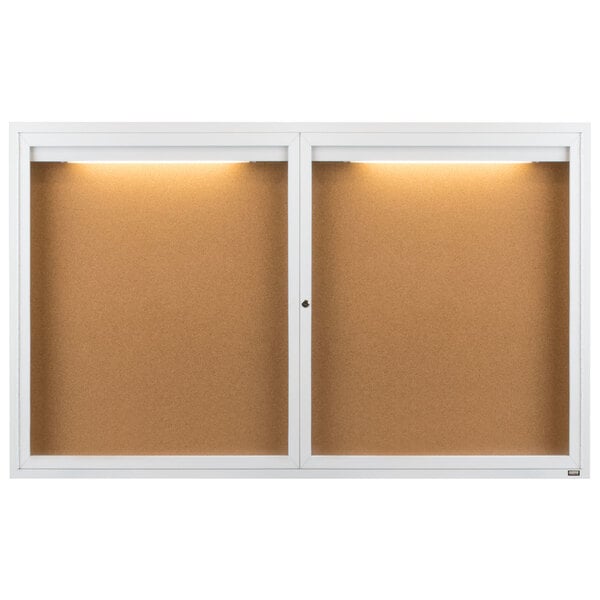 A white Aarco enclosed bulletin board with lights.