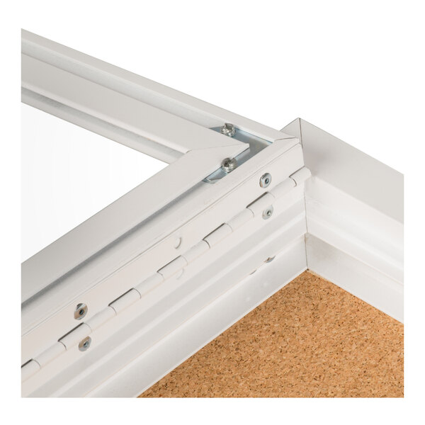 A close-up view of the corner of a white metal-framed bulletin board cabinet with a hinged door and corkboard interior.
