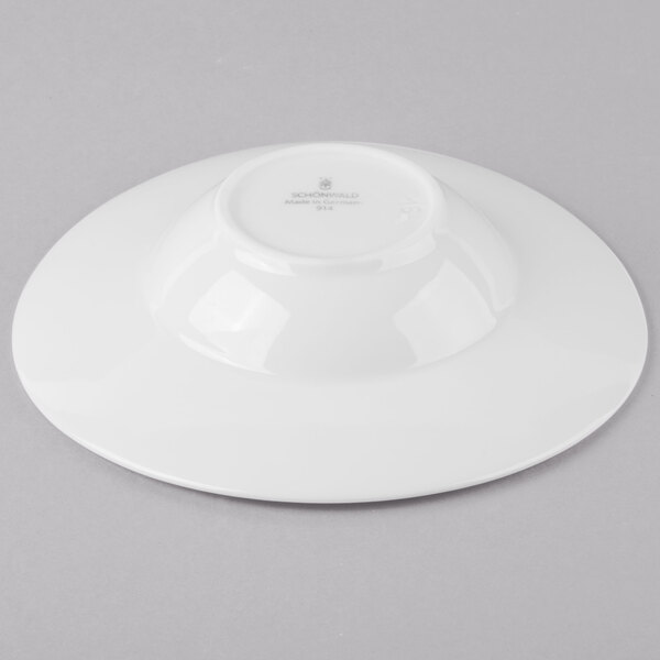 A white plate with a white rim and a small bowl on it.