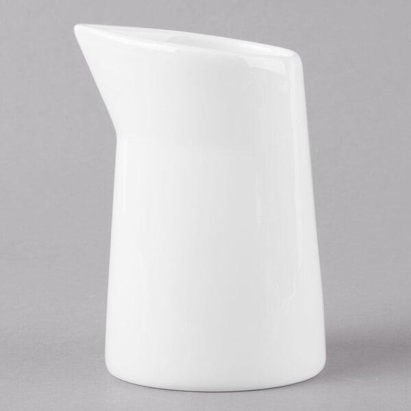 A Schonwald white ceramic creamer with a white handle.
