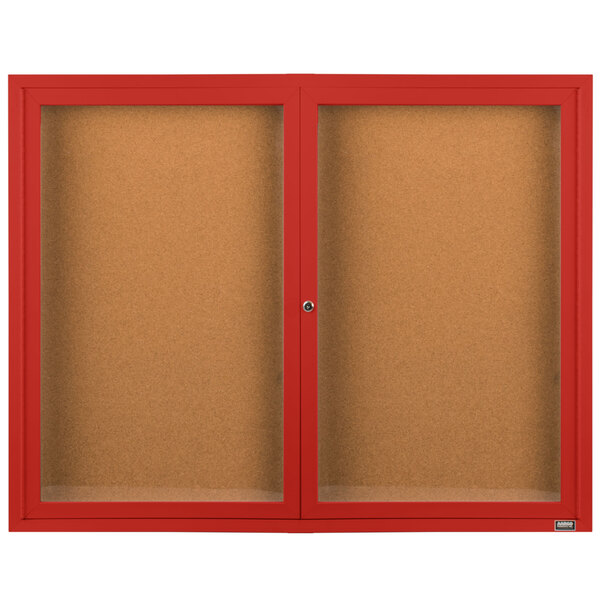 An Aarco red indoor bulletin board cabinet with two doors enclosing cork boards.