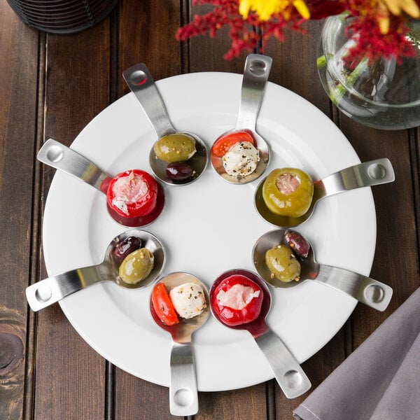 A Schonwald porcelain tapas plate with a spoon holding green olives and red peppers.