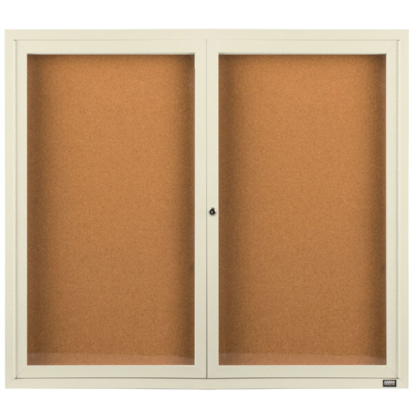 A white cabinet with a white framed bulletin board with glass doors.