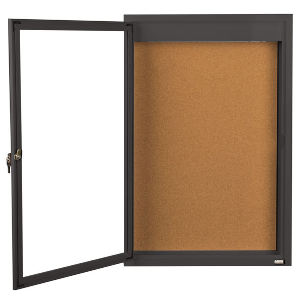 A brown bulletin board with a bronze frame and glass door.