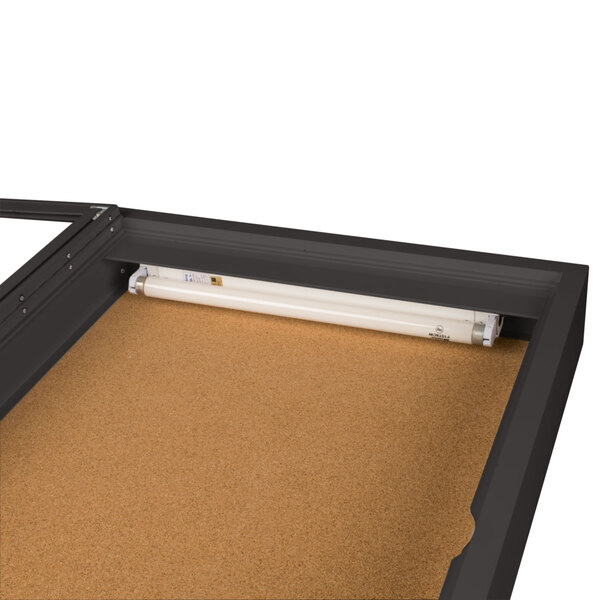 An Aarco bronze indoor lighted bulletin board cabinet with one door.