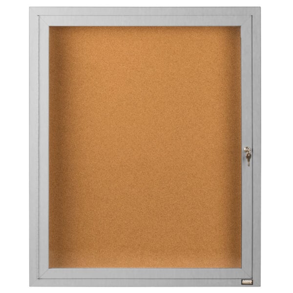 A satin anodized finish white framed bulletin board with a glass door and key.