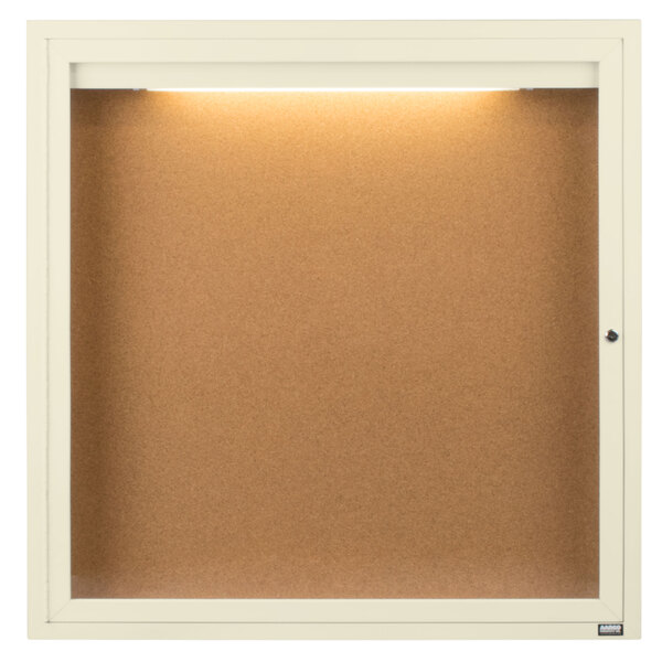 An ivory Aarco enclosed bulletin board with a light inside.