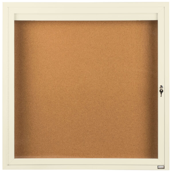 An ivory Aarco enclosed bulletin board with a glass door.