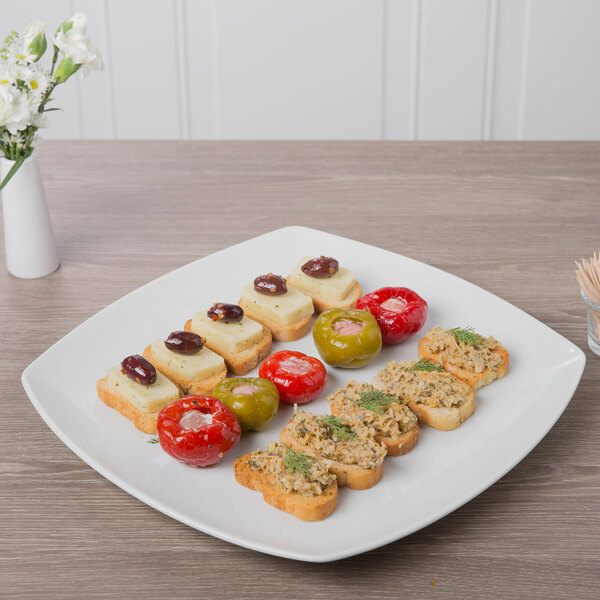 A Schonwald continental white porcelain plate with appetizers including olives, tomatoes, and cheese.