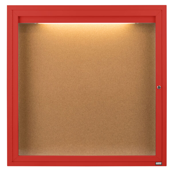 A red framed enclosed bulletin board with a light.