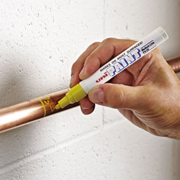 Person writing on copper pipe with yellow medium point paint marker