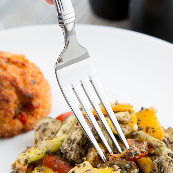 A Libbey stainless steel dinner fork in a plate of food.