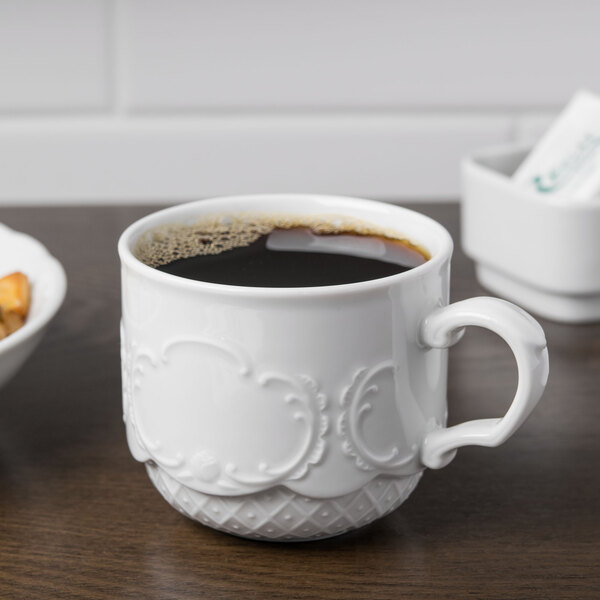 A Schonwald white porcelain cup filled with brown liquid on a white background.