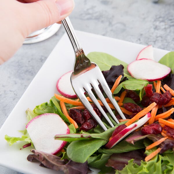 A World Tableware Resplendence stainless steel salad fork on a plate of vegetables.