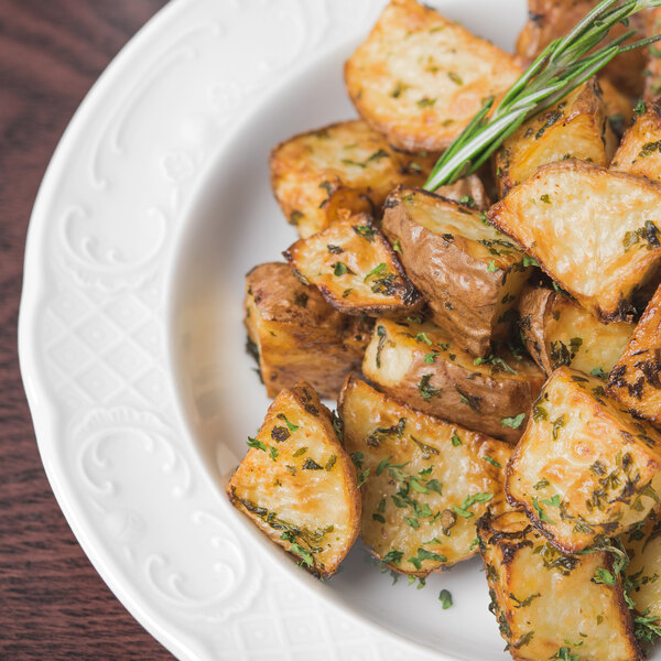 A Schonwald Marquis deep porcelain soup bowl filled with roasted potatoes with rosemary.