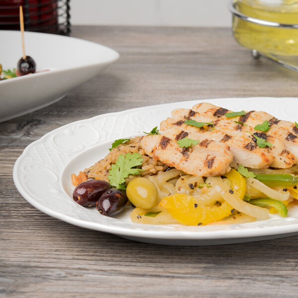 A Schonwald oval porcelain platter with food on a table.