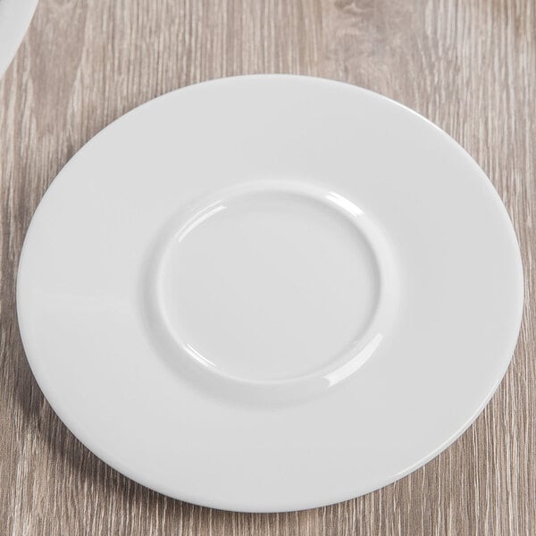 A wood surface with a Schonwald white porcelain saucer on a white plate.