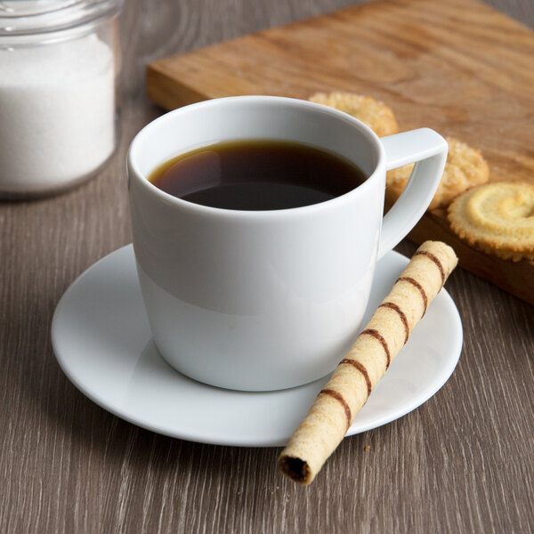 A Schonwald white porcelain cup of coffee and a cookie on a plate.