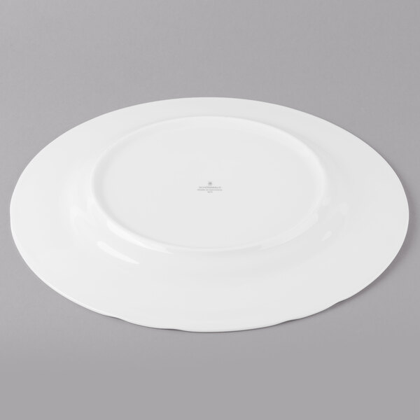 A white Schonwald porcelain plate with a small circular design on a gray surface.