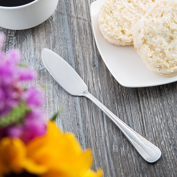 A Libbey stainless steel butter spreader on a plate with biscuits.