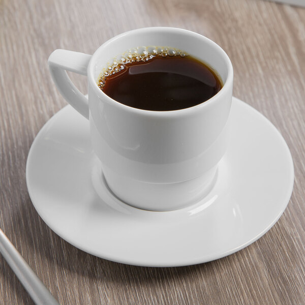 A Schonwald continental white porcelain stackable mug filled with coffee on a saucer.