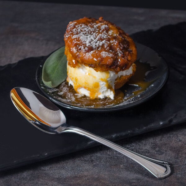 A dessert on a black plate with a World Tableware Resplendence stainless steel dessert spoon.