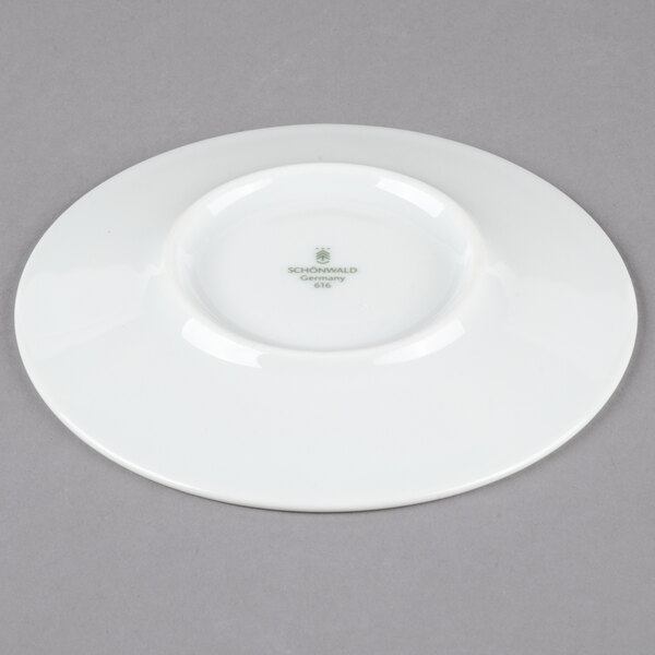 A white Schonwald porcelain saucer with green writing on it.