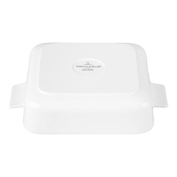 A white, square porcelain dish with handles on two sides, shown upside down.