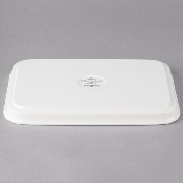 A white rectangular porcelain lid with a logo on it.