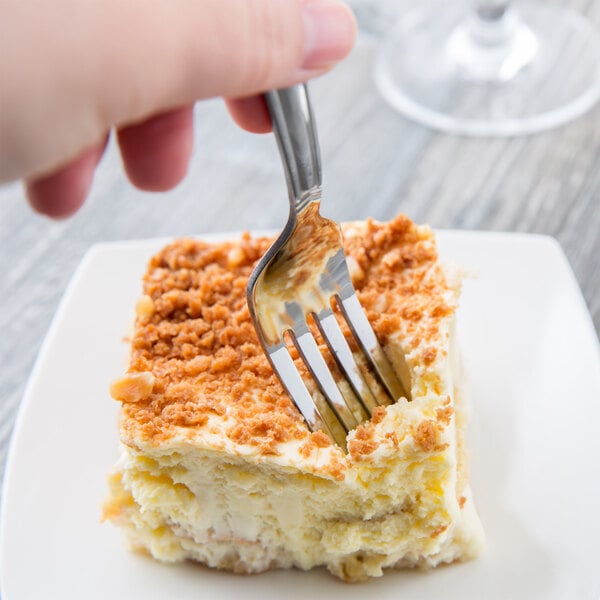 A Libbey stainless steel heavy weight utility/dessert fork in a piece of cake.