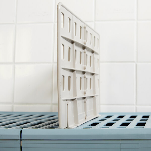 A white plastic MetroMax Q shelf divider on a white shelf.
