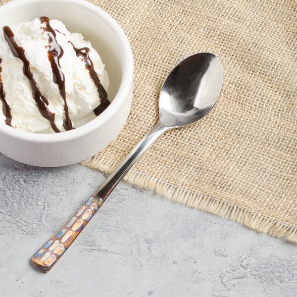 A bowl of ice cream with chocolate syrup and a Master's Gauge 18/10 stainless steel dessert spoon.