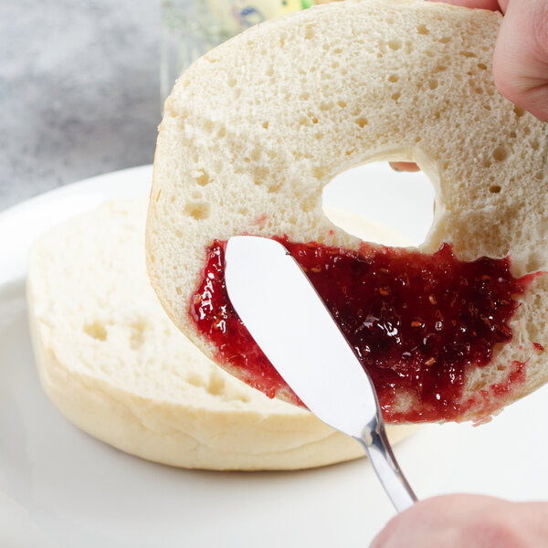A person spreading jam on a piece of bread with a Master's Gauge Pebblestone butter spreader.