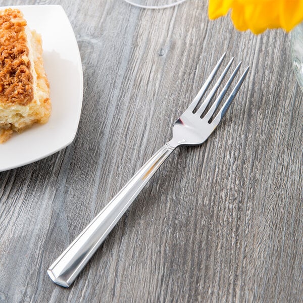 A Libbey stainless steel dinner fork on a table next to a plate of food.