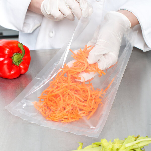 A person in white gloves using a VacPak-It chamber vacuum packaging bag to hold shredded carrots.