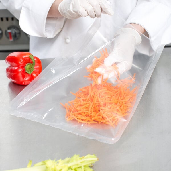 A person in white gloves using a VacPak-It 12" x 15" vacuum packaging bag to hold shredded carrots.