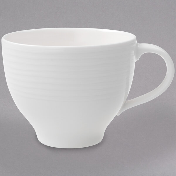 A close-up of a Villeroy & Boch white porcelain cup with a handle.