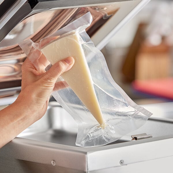 A hand holding a VacPak-It plastic bag of cheese.