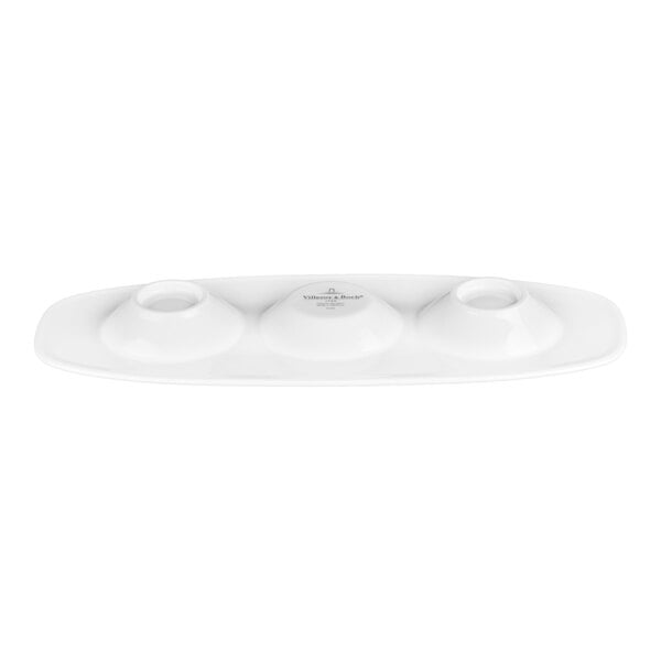 A white oval plate with three round, raised compartments evenly spaced along its length.