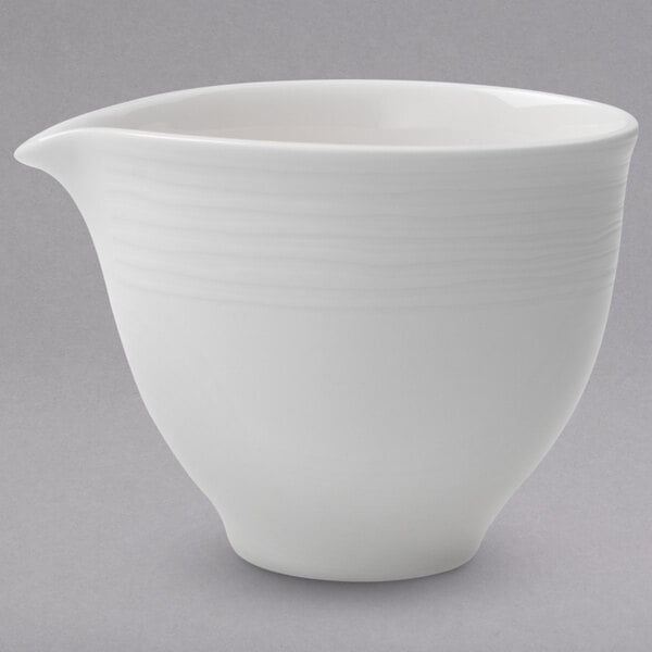 A white porcelain creamer with a handle.