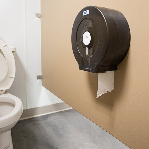 A Lavex Universal Jumbo Toilet Paper Roll in a toilet paper dispenser on a wall.