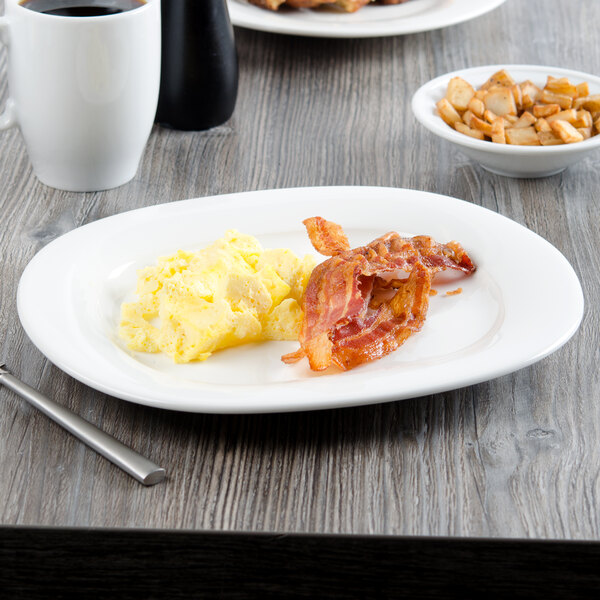 A white Villeroy & Boch porcelain oval platter with eggs and bacon on a table.