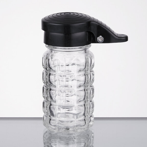 A clear glass jar with a black top.