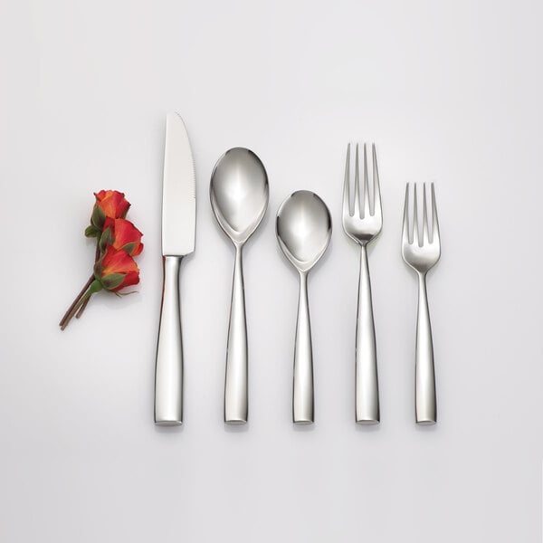 An Arcoroc stainless steel dinner spoon with a white flower design.