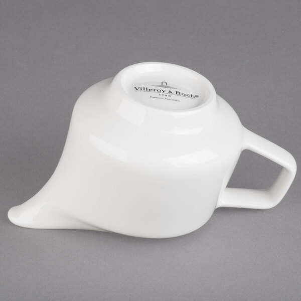 A white porcelain creamer with a handle.