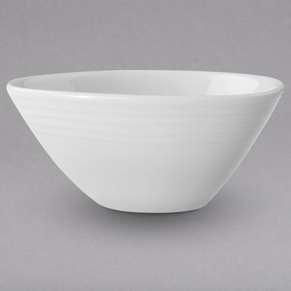 A Villeroy & Boch white porcelain bowl with a curved edge on a white background.
