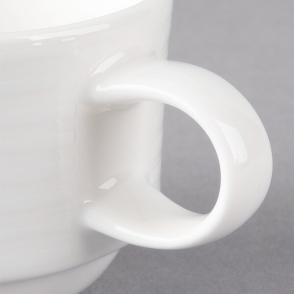A close-up of a Villeroy & Boch white porcelain coffee cup with a handle.